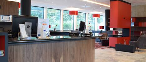 A modern reception area with a curved wooden counter, multiple computer stations, and red accent lighting.