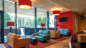 Eine moderne Lobby mit großen Fenstern, roten Wänden und zwei Sofas.