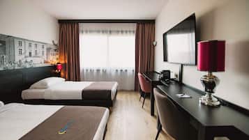 A hotel room with two beds, a desk with a computer, a TV, and a red lamp.