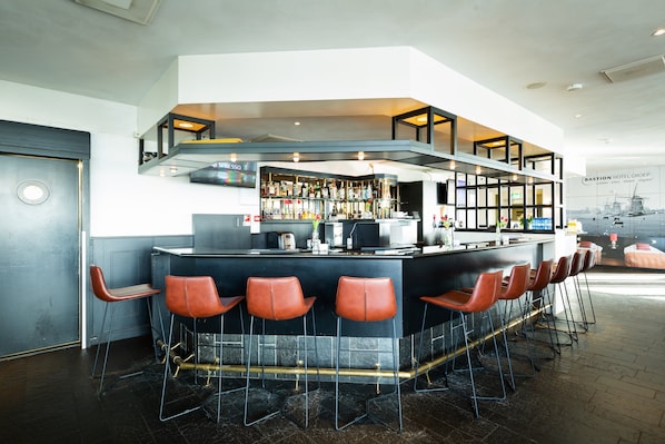 Un área de bar moderna con una barra curva, varios taburetes y una variedad de botellas y vasos.