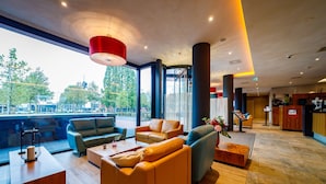 Un vestíbulo moderno con sofás de cuero, un mostrador de recepción de madera y amplios ventanales con vistas a la ciudad.