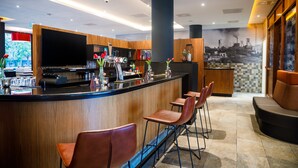 Un área de bar moderna con detalles de madera, un televisor de pantalla plana y taburetes de bar.