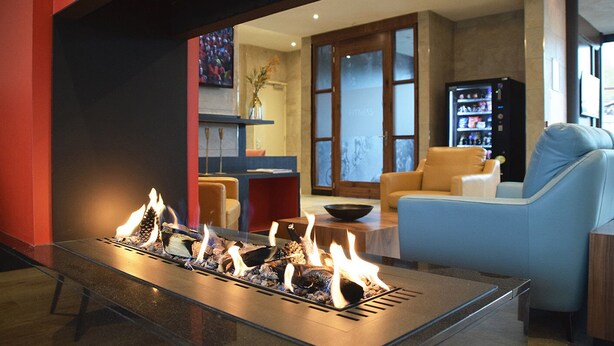 Un vestíbulo moderno con una chimenea central, zona de estar y máquina expendedora.