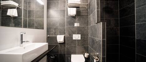 A modern bathroom with a white sink, a toilet, and a shower area.