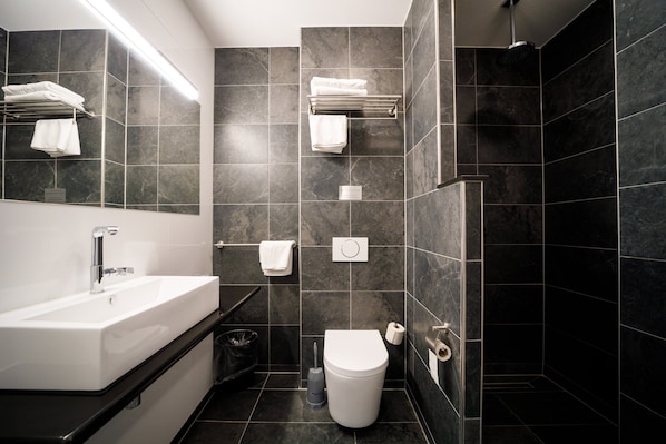 Un baño moderno con lavamanos blanco, inodoro y zona de ducha.