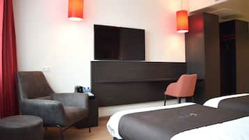 A hotel room with two beds, a TV, a desk, and two chairs.