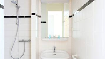 A bathroom with a shower, sink, and mirror.