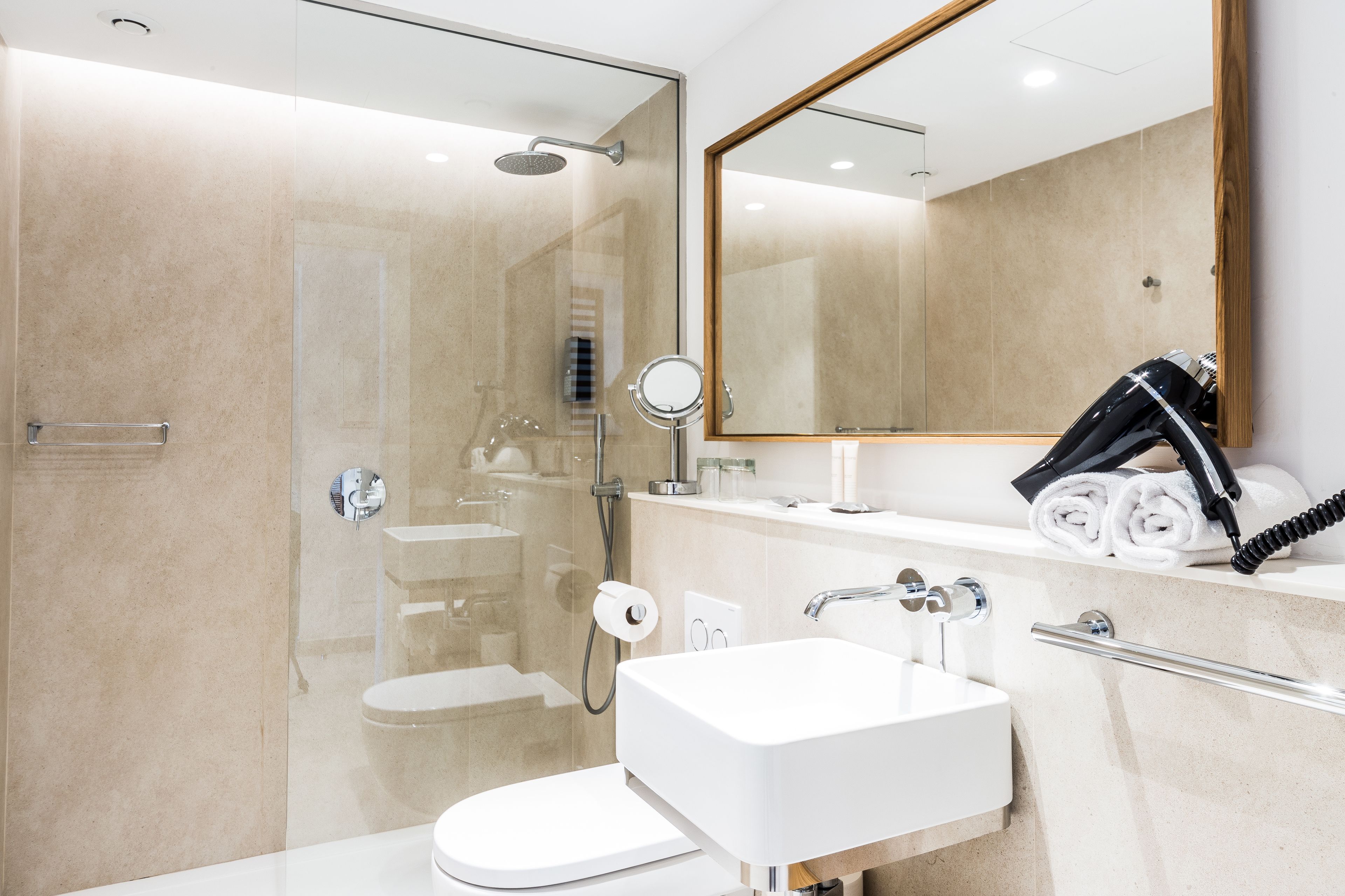 A modern bathroom with a glass-enclosed shower, a white sink, and a large mirror.