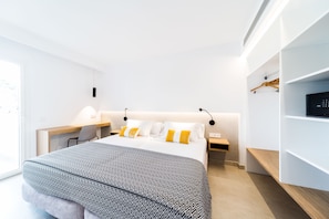 Una habitación de hotel moderna con una cama, mesitas de noche, un escritorio y un televisor.