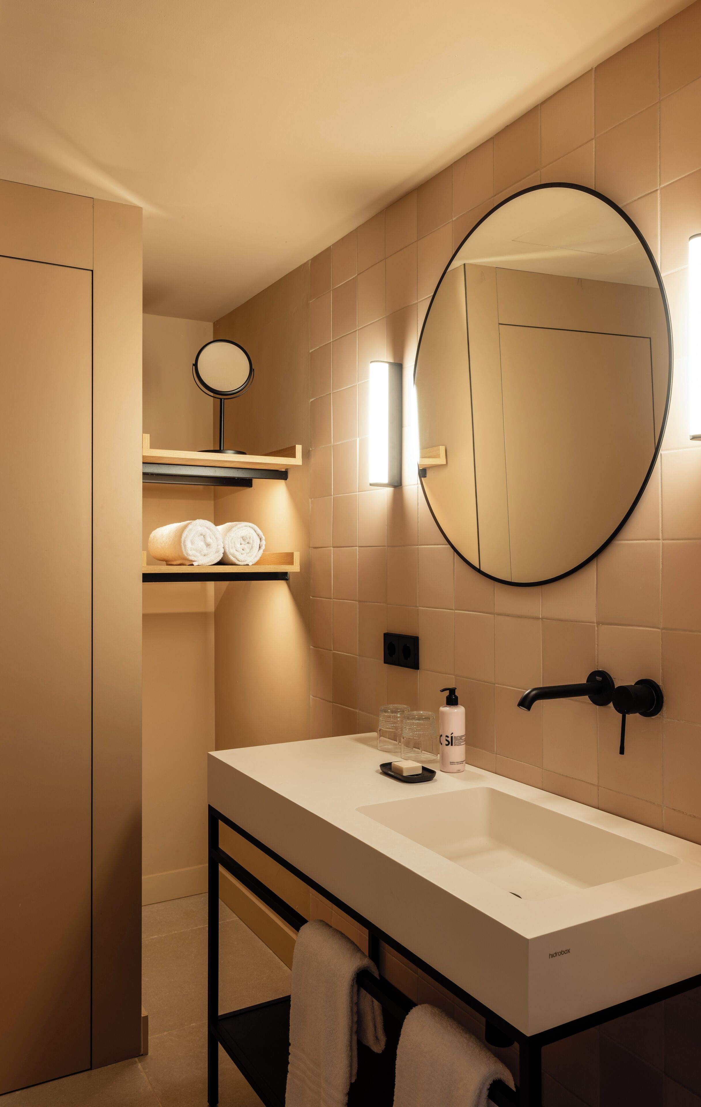 A modern bathroom with a white sink, a large mirror, and a towel rack.