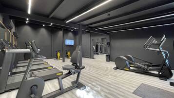 Un gimnasio moderno con cintas de correr, máquinas de pesas y una pantalla de televisión.