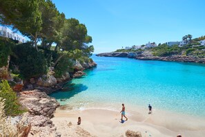 A coastal scene with clear turquoise waters, rocky cliffs, and white buildings. - Inturotel Esmeralda Park (Santanyi)