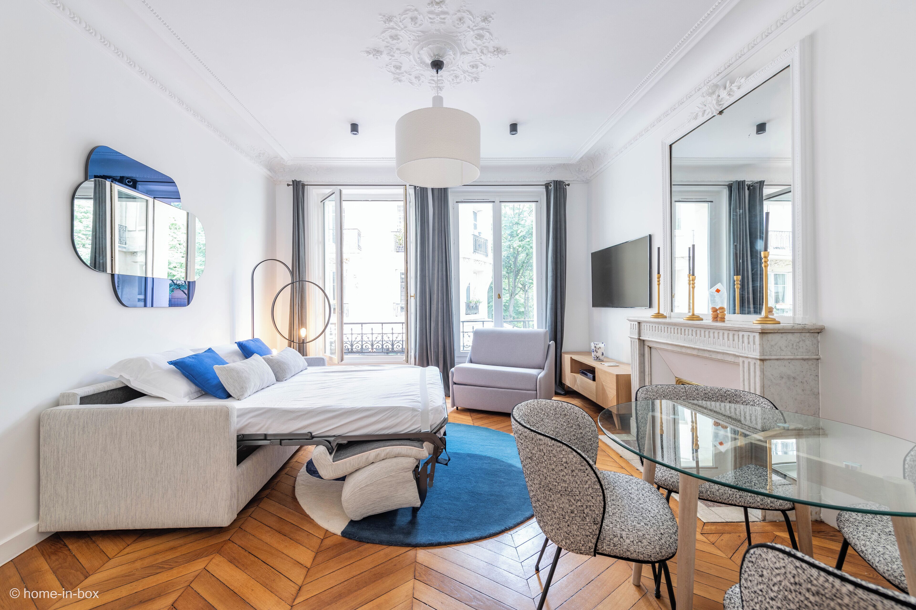 Um quarto moderno com uma cama, um espaço de estar, uma mesa de vidro e uma televisão.