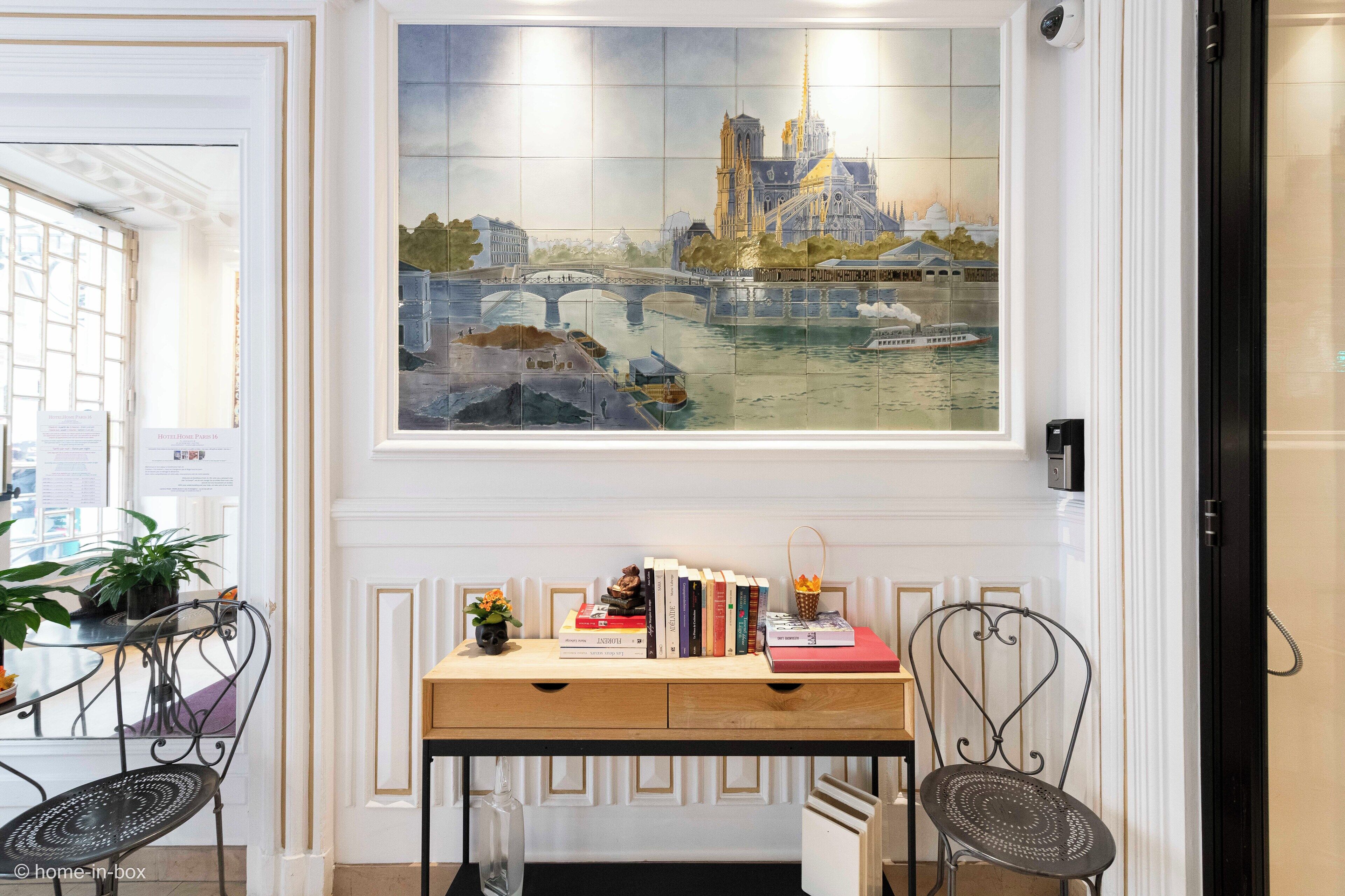 A room with a desk, two chairs, a painting of a cityscape, and a door with a security camera.