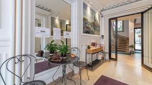 A hotel lobby with a dining area featuring a round table, chairs, and a potted plant. - HotelHome Paris 16 (Paris)