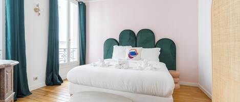Un dormitorio con una cama grande, un banco y una ventana con cortinas.