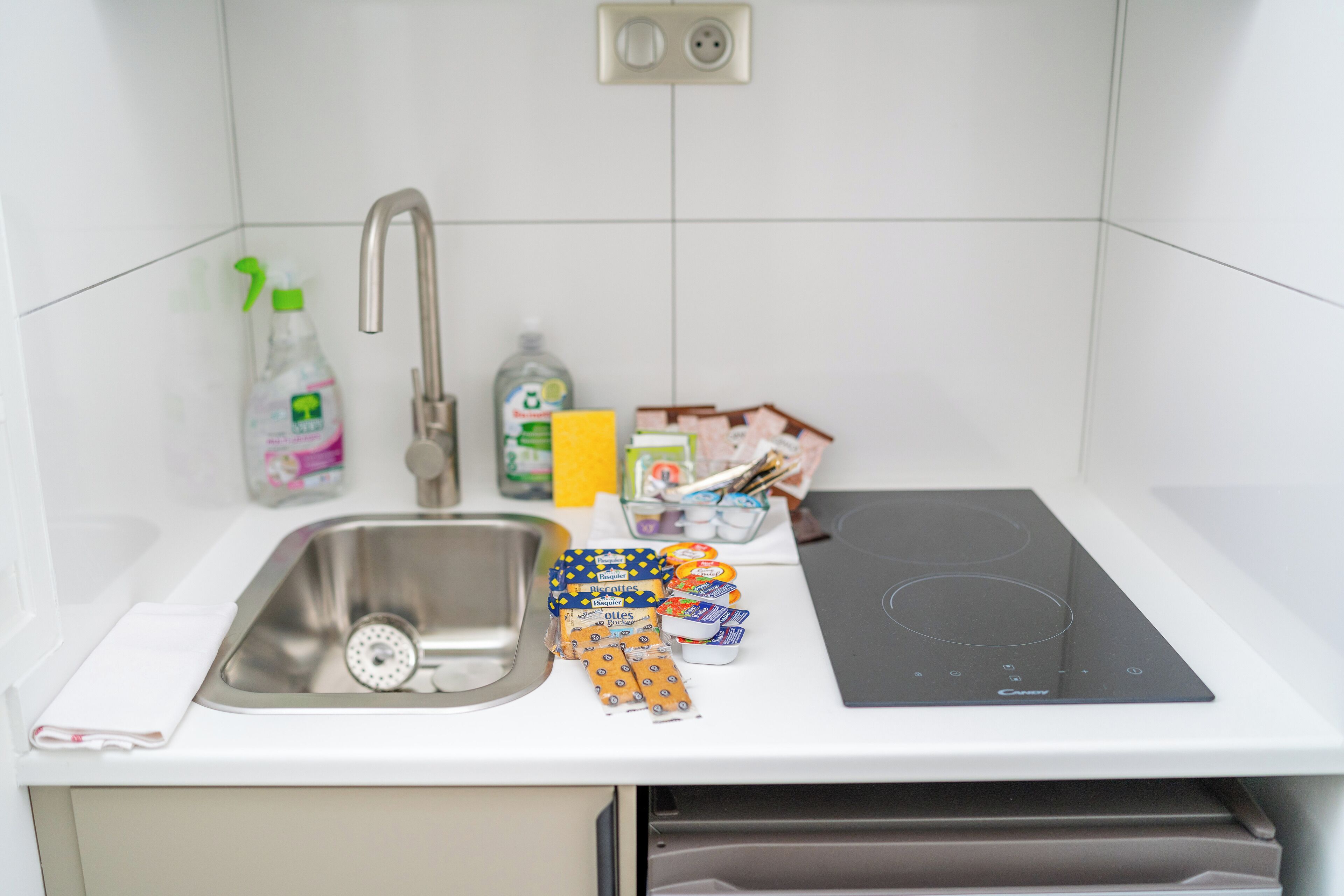 A kitchen with a stainless steel sink, a built-in stove, and various kitchen items on the counter.