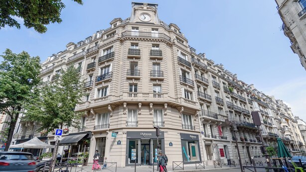 A historic building with a corner entrance, multiple balconies, and a clock tower. - HotelHome Paris 16 (Paris)