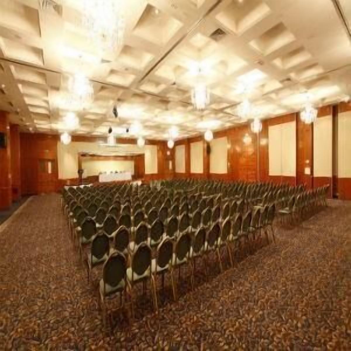A conference room with rows of chairs, a podium, and a carpeted floor.