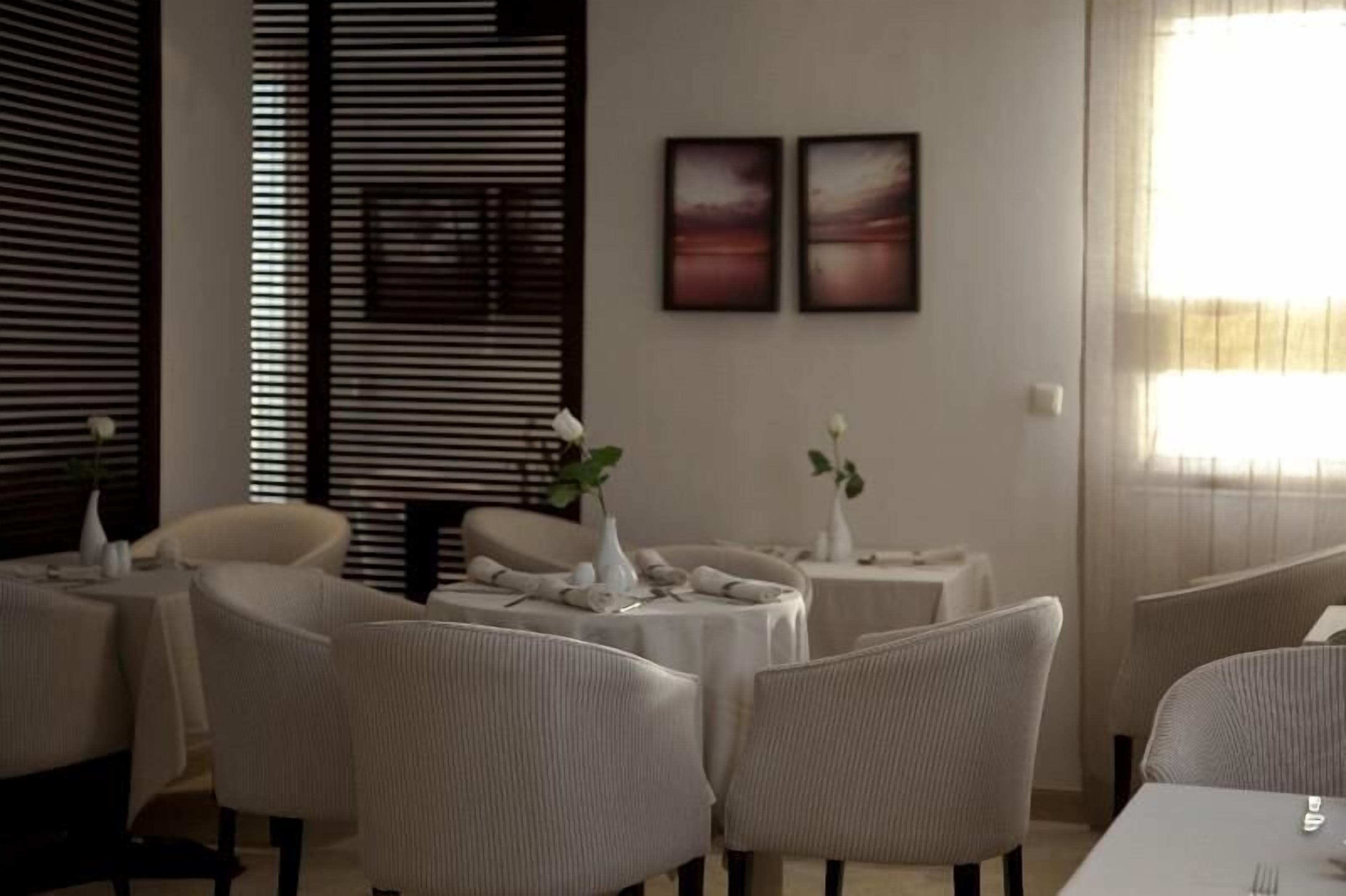 A dining area with round tables, chairs, and two framed pictures on the wall.