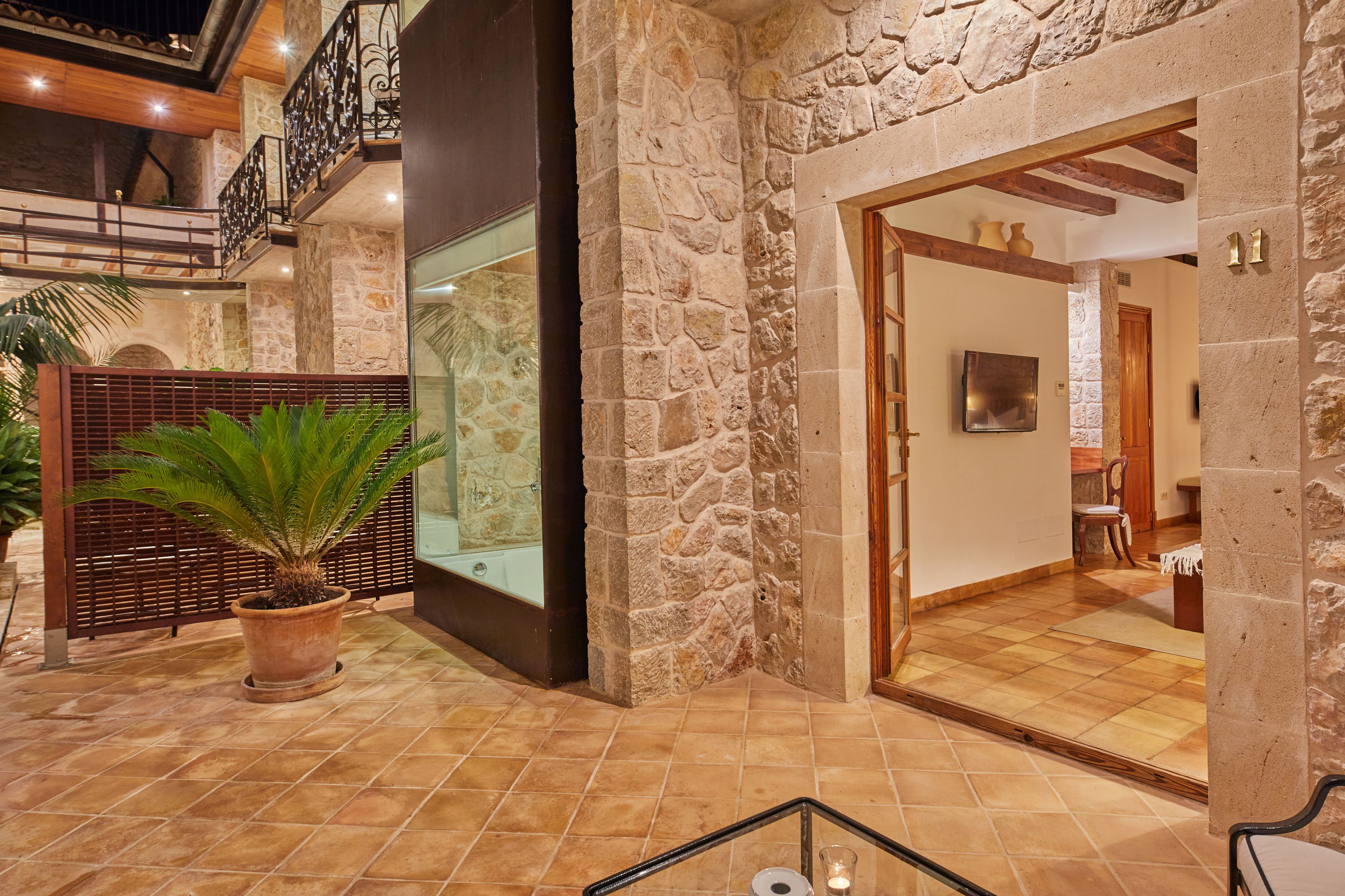 A spacious indoor area with stone walls, a wooden staircase, and a potted plant.