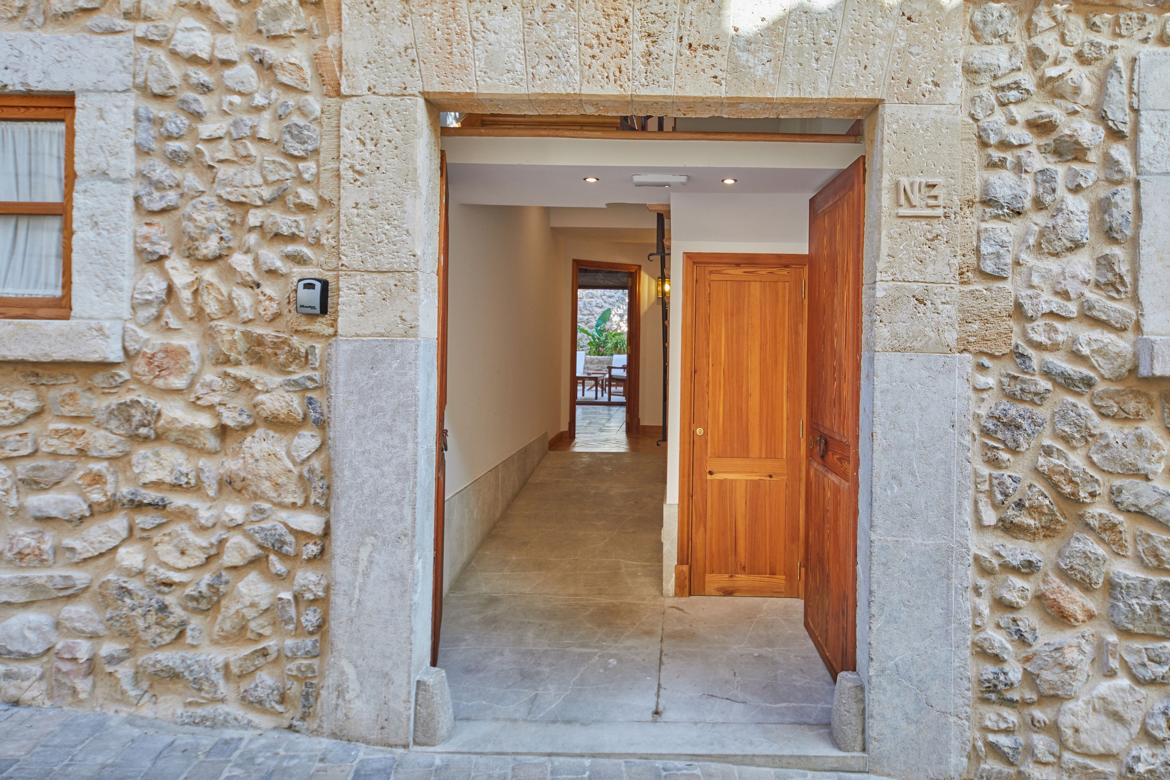 Vestíbulo de un edificio de piedra con una puerta de madera y una habitación visible al fondo.