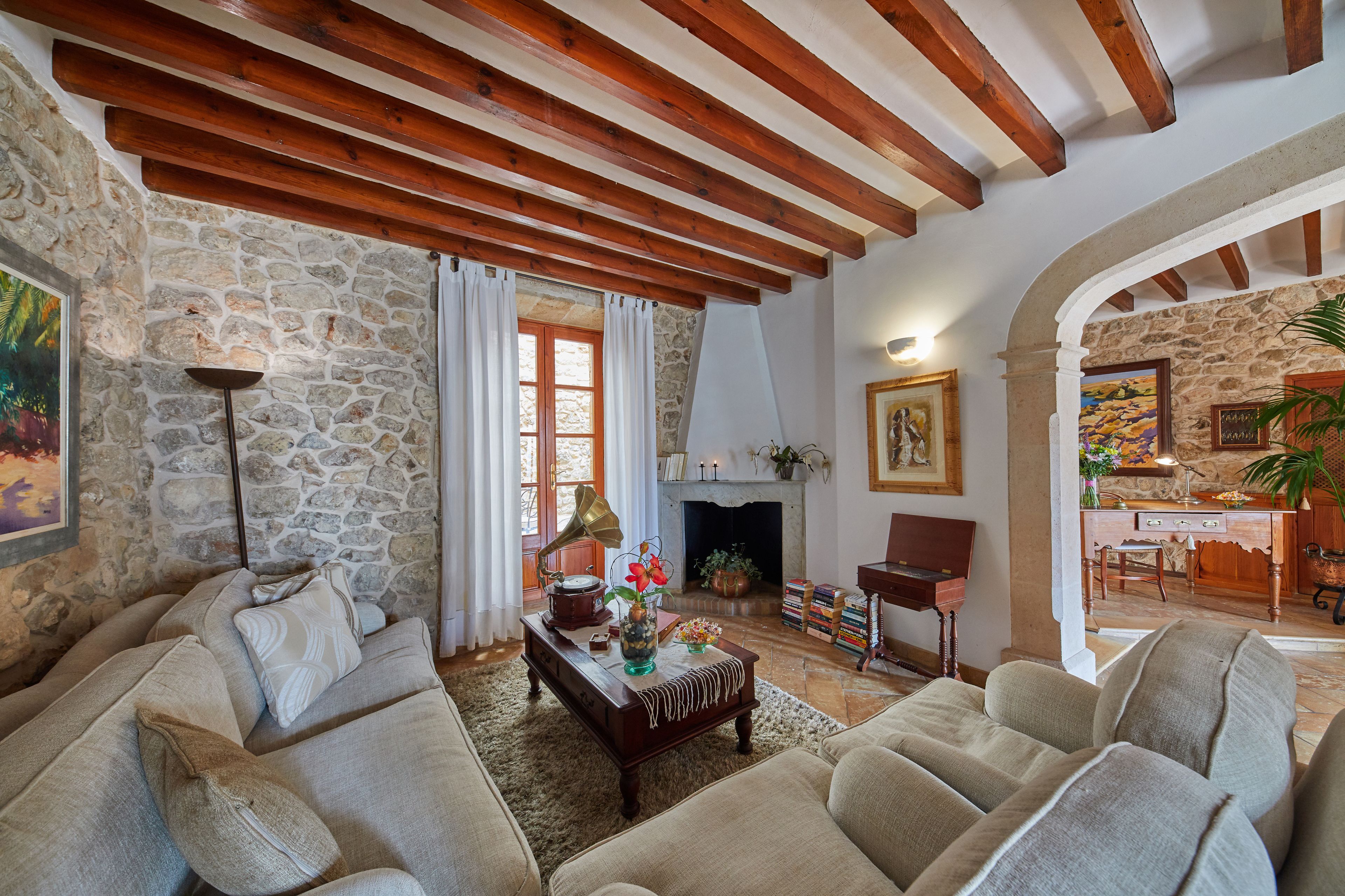 Un salon chaleureux avec des murs en pierre, des poutres en bois, une cheminée et des sièges confortables.