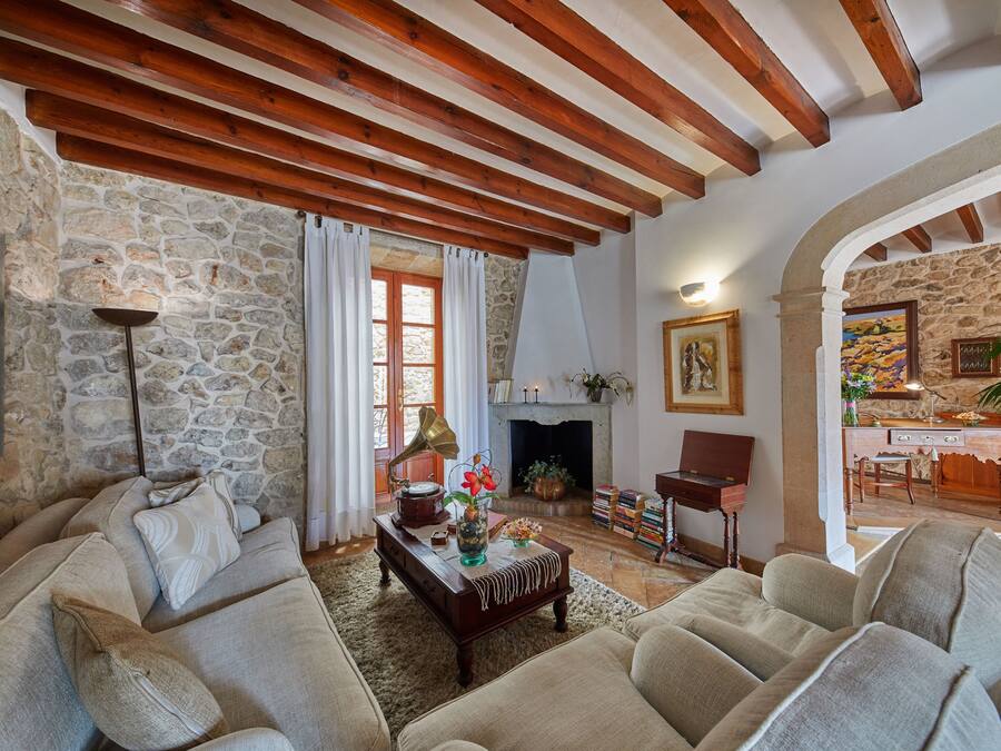 A cozy living room with stone walls, wooden beams, a fireplace, and comfortable seating.