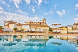 Una piscina al aire libre, sombrillas, tumbonas