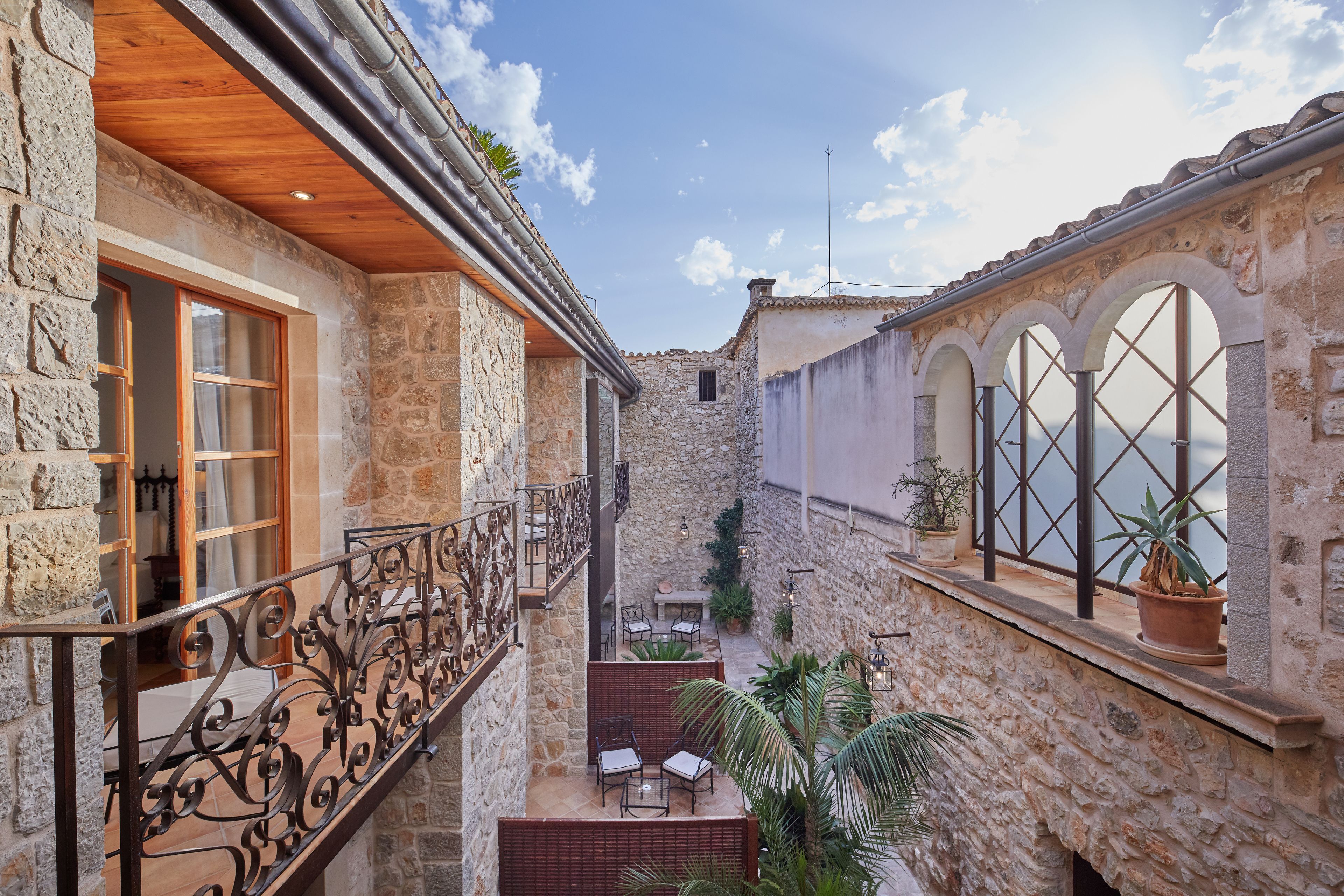 A stone building with a balcony, outdoor seating, and potted plants.