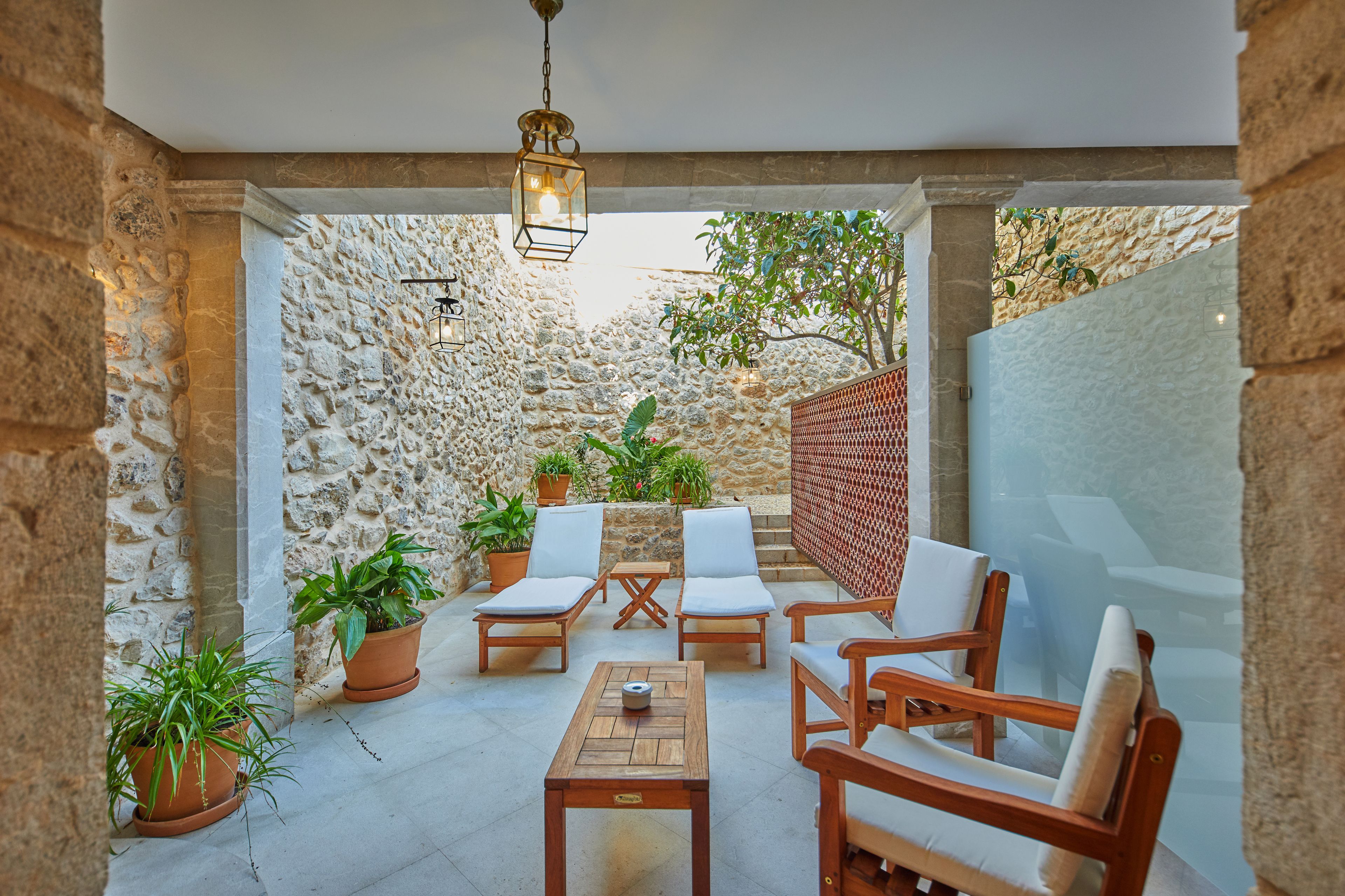 Eine Terrasse mit Holzmöbeln, Topfpflanzen und einer Steinmauer.