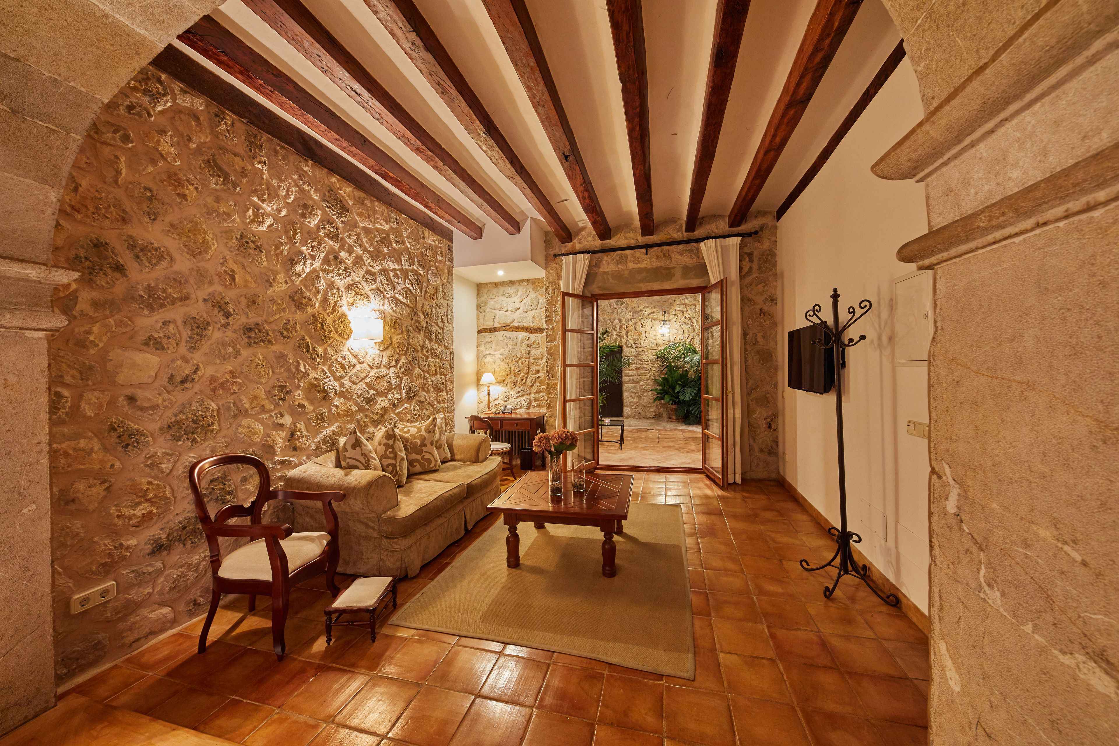 Una habitación acogedora con paredes de piedra, vigas de madera, un sofá, una mesa de centro y una lámpara.