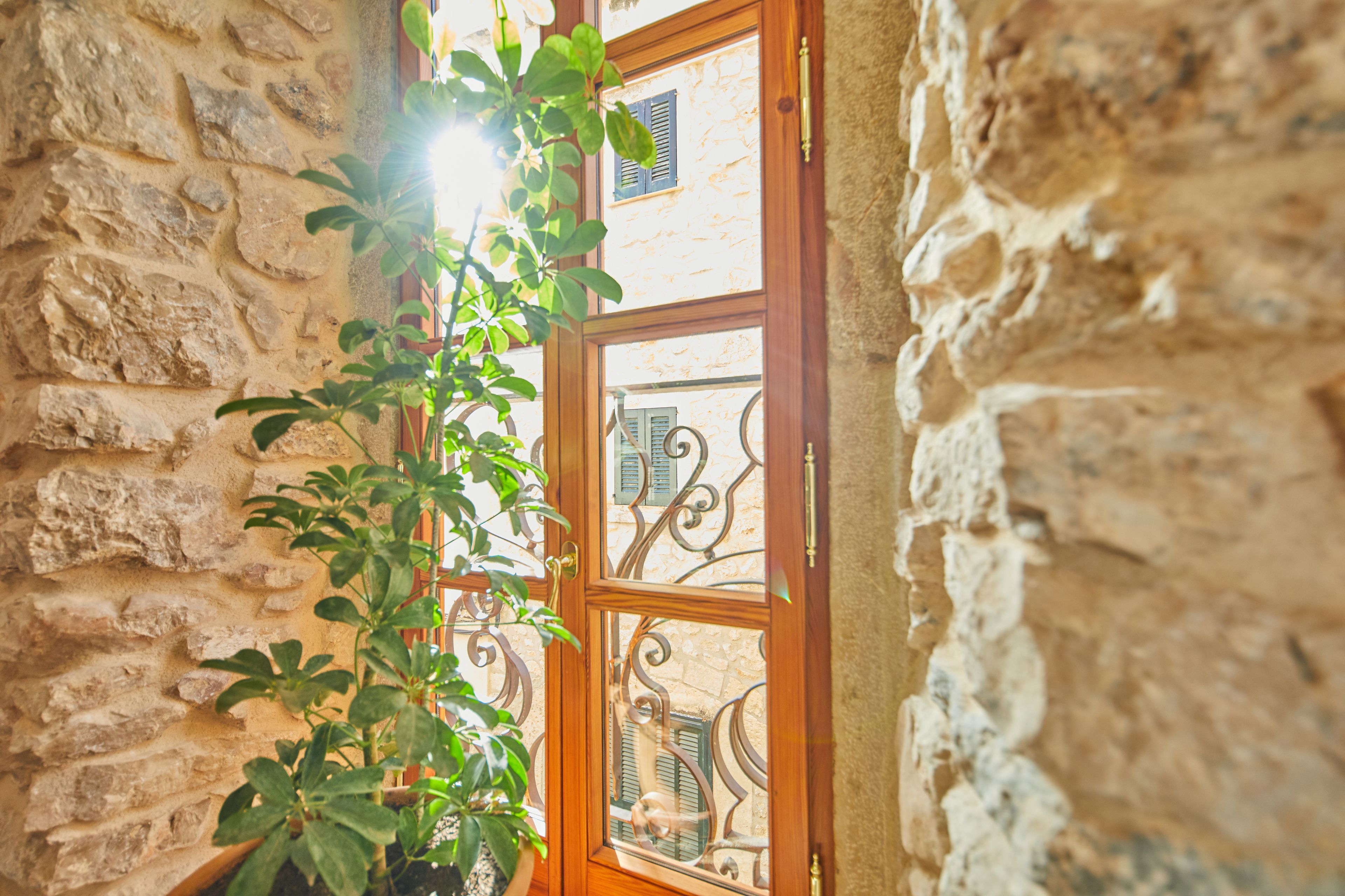 Pared de piedra con una puerta de madera que tiene un panel de vidrio y detalles decorativos de metal.
