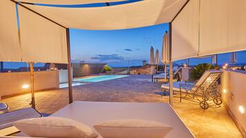 Una piscina al aire libre, sombrillas, sillones reclinables de piscina