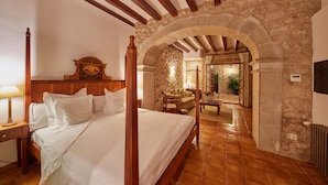 A four-poster bed in a room with stone walls and wooden beams. - Cas Comte Suites & Spa - Adults Only (Lloseta)