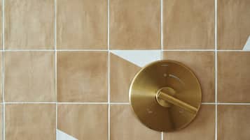 Een badkamer met een betegelde muur en een goudkleurige kraan.