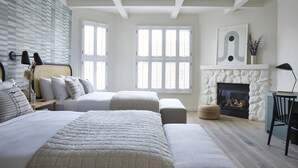 Quarto com cama grande, duas camas menores, lareira e vista para o exterior.