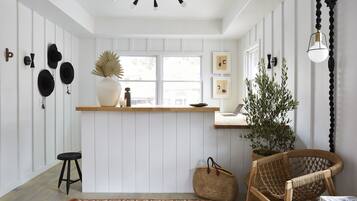 A kitchen with white paneling, a wooden countertop, and a hanging light fixture.