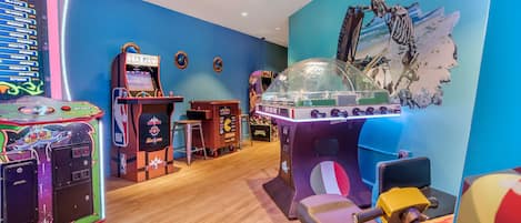 A room with arcade games, a basketball-themed wall, and a large skeleton decoration.