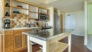 Una cocina moderna con armarios de madera, encimera de acero inoxidable y un microondas empotrado.