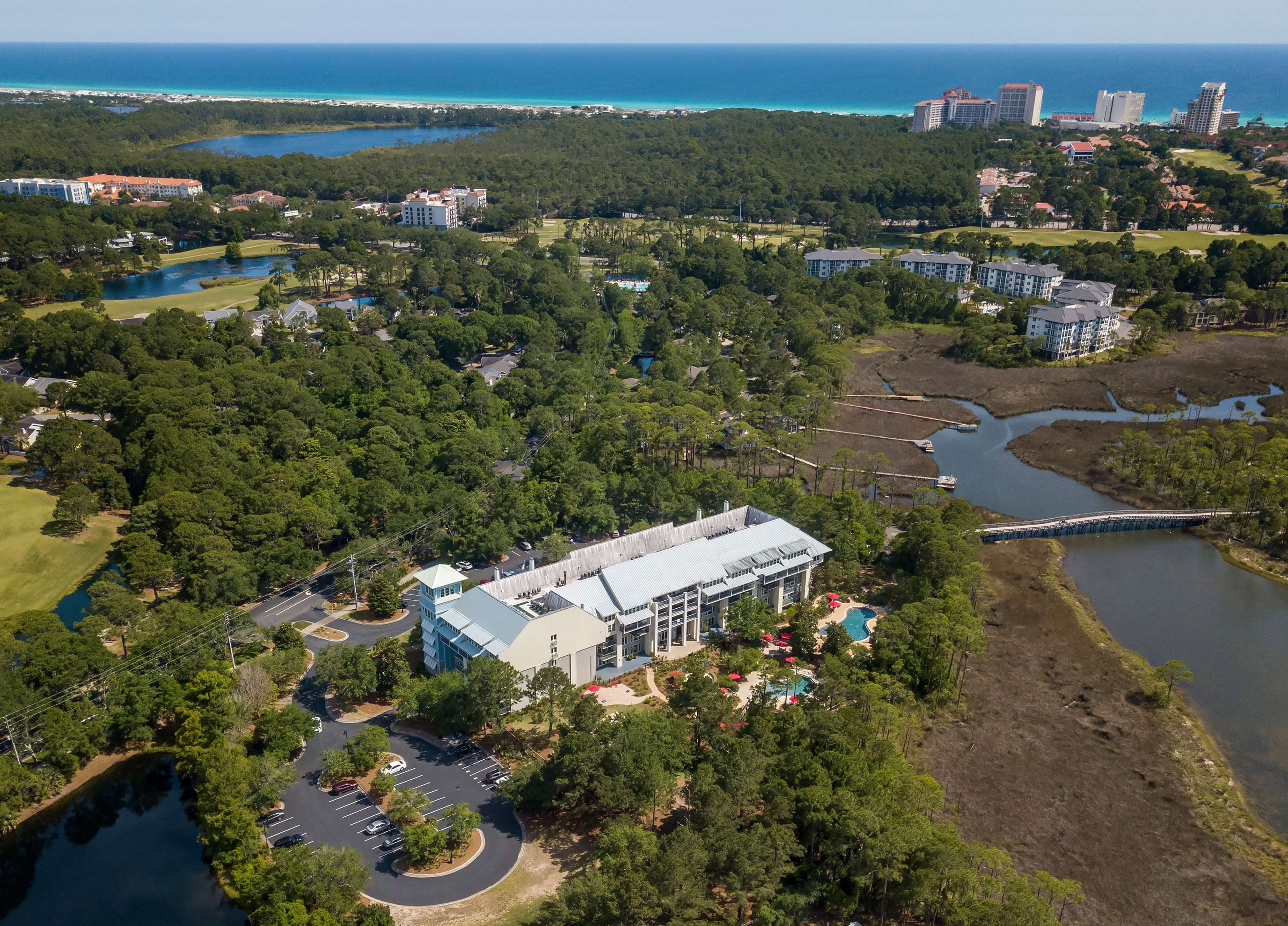 Une vue aérienne d’un complexe hôtelier comprenant un grand bâtiment, un terrain de golf et une étendue d’eau.