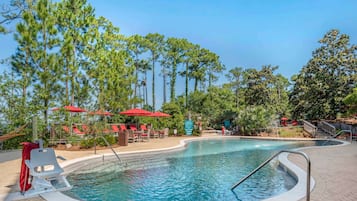 Una piscina al aire libre, sombrillas, sillones reclinables de piscina