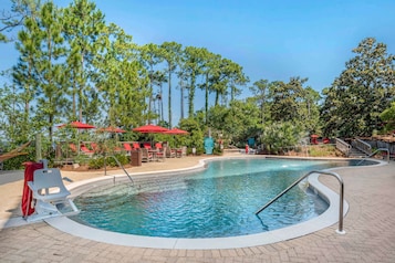 Una piscina al aire libre, sombrillas, sillones reclinables de piscina