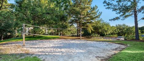 Una rete da pallavolo circondata da alberi e da una recinzione di legno.
