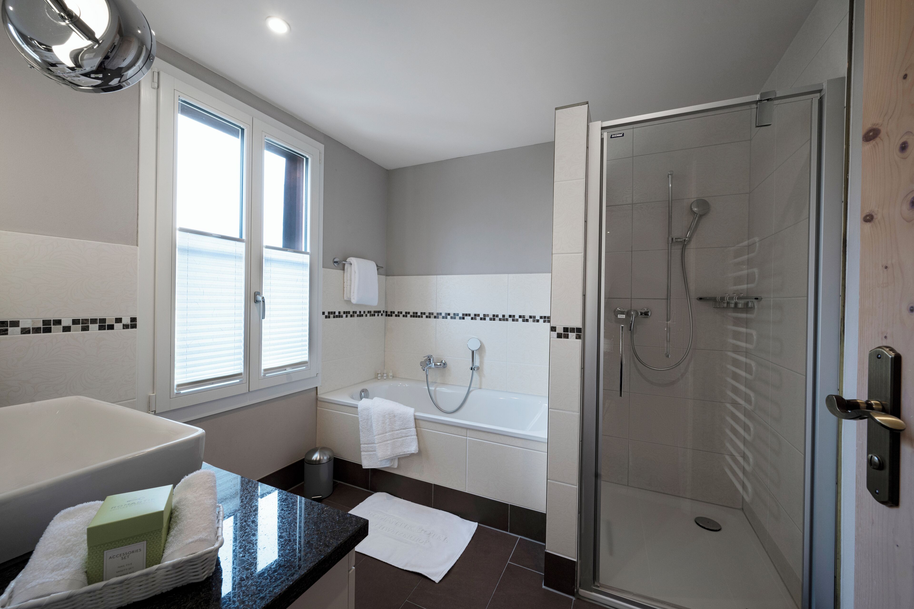 Une salle de bain moderne dotée d’une douche à parois de verre, d’une baignoire et d’un grand lavabo.