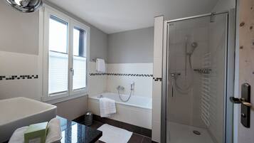 Une salle de bain moderne dotée d’une douche à parois de verre, d’une baignoire et d’un grand lavabo.