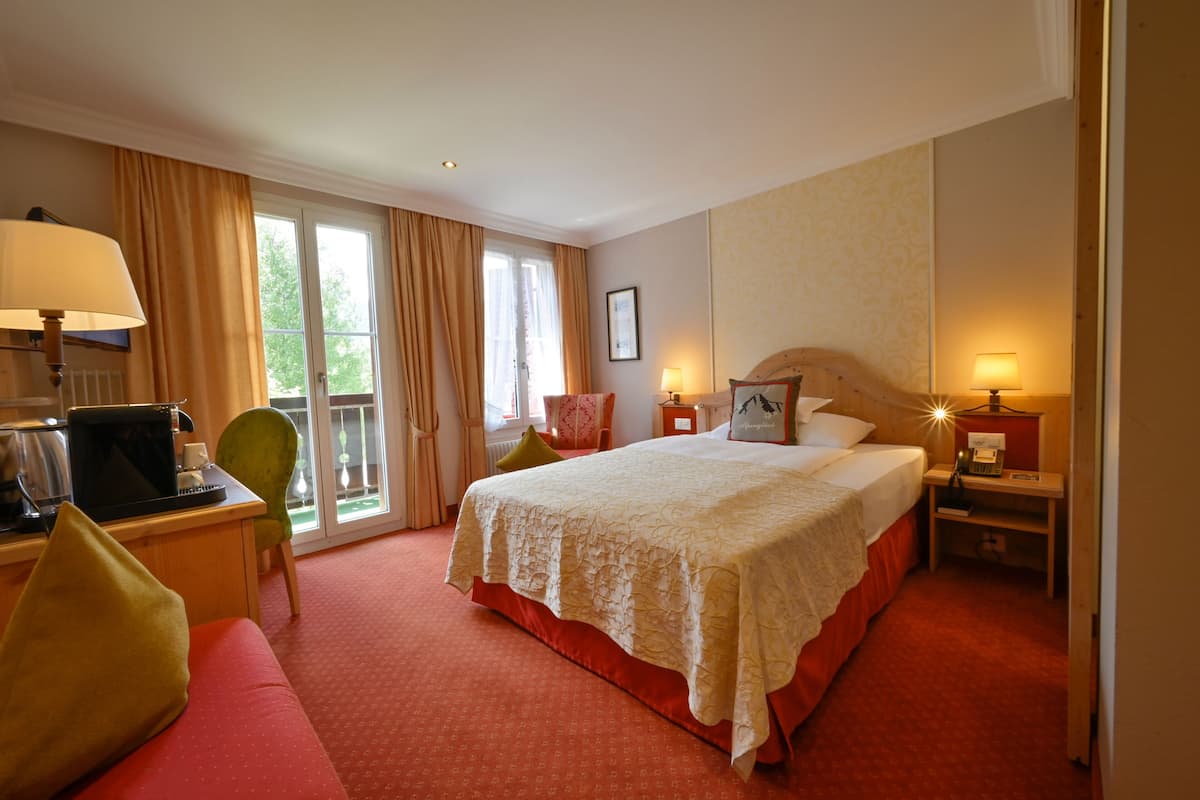 Habitación de hotel con una cama grande, un escritorio con una computadora, una silla y un sofá.