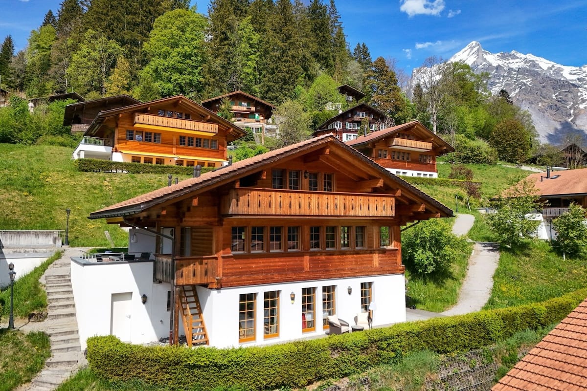 Un chalet de madera con balcones, una escalera y vistas a la montaña.