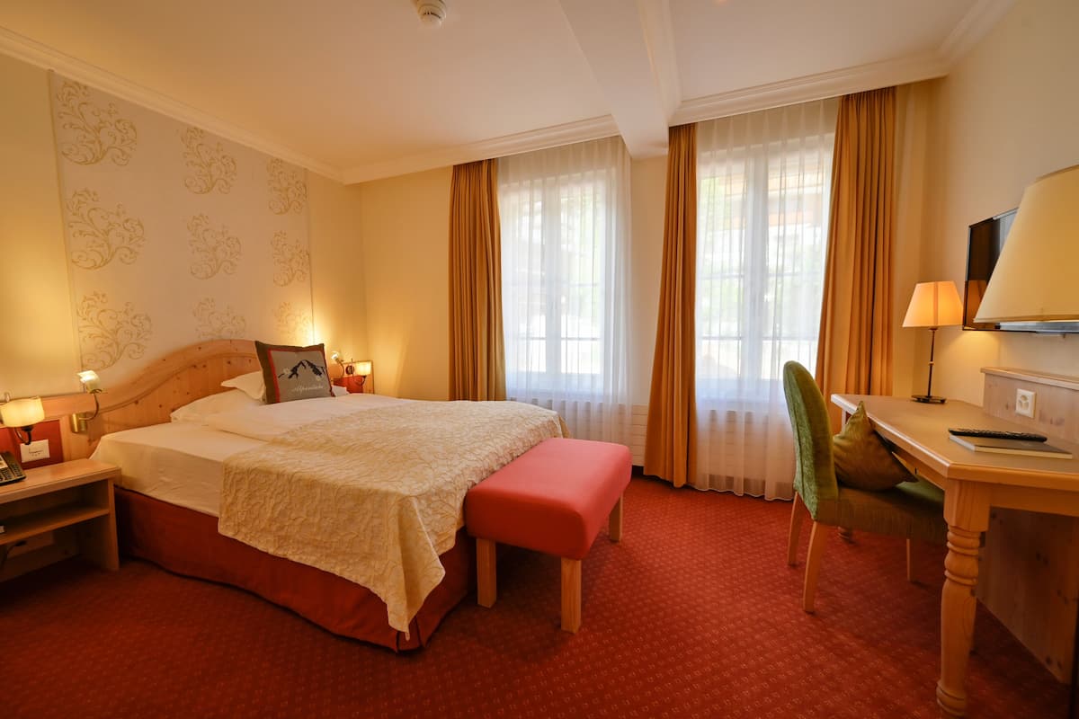 Una habitación de hotel con una cama grande, un escritorio, una silla y un televisor.