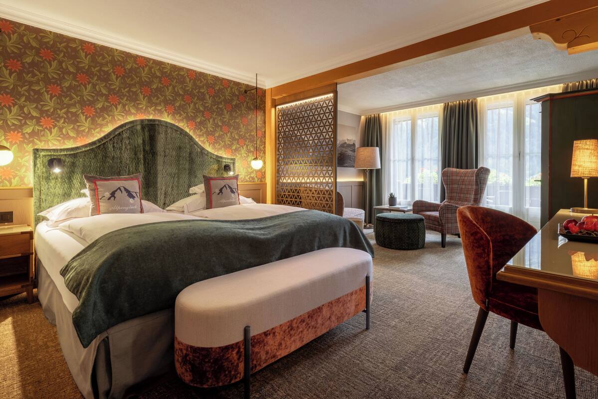 Una habitación de hotel con una cama grande, un escritorio, una silla y un cabecero decorativo.